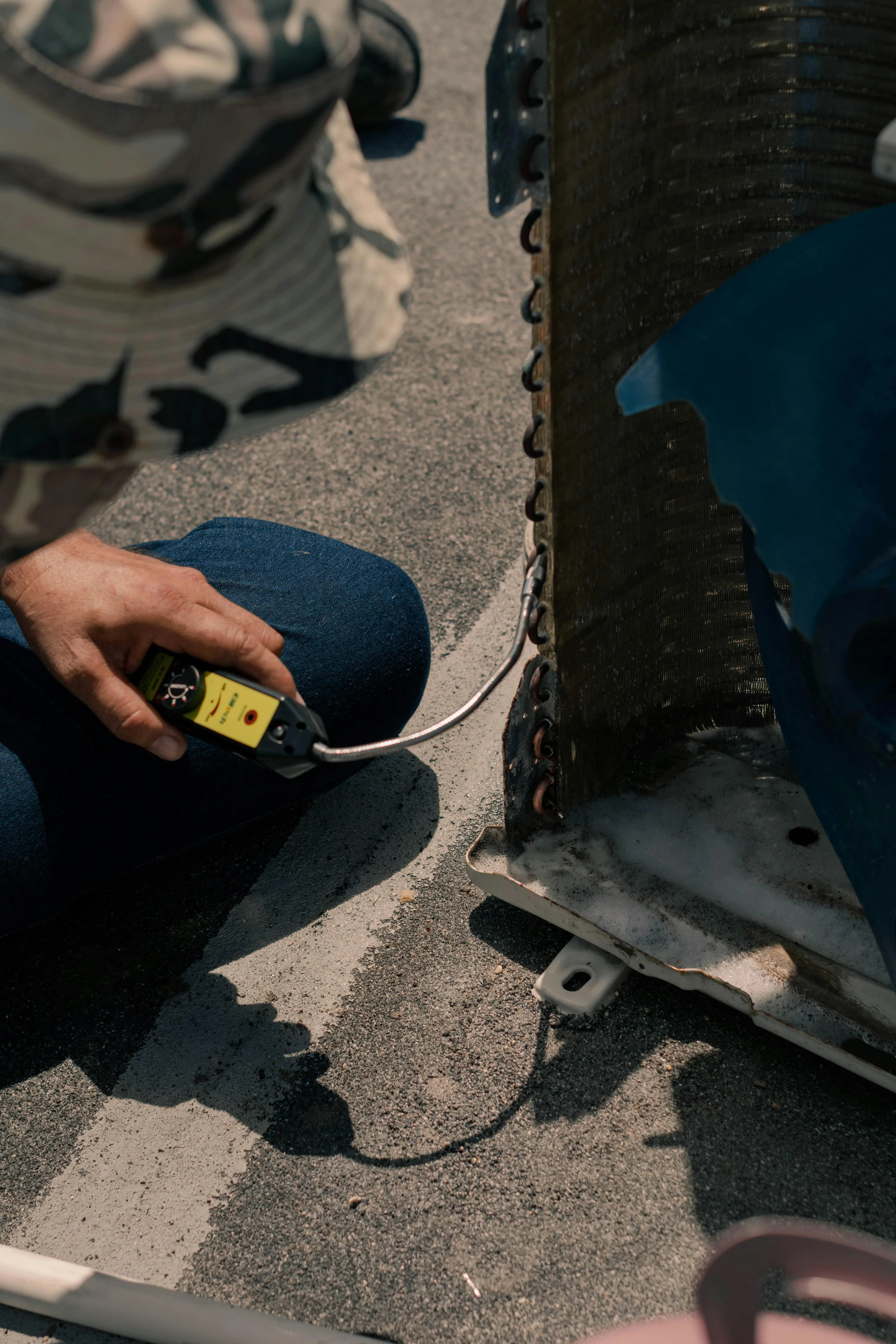 HVAC technician using a diagnostic tool on a rooftop condenser unit
