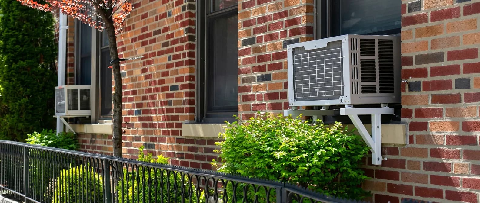 Window AC units mounted on a NYC brick building — cooling assistance programs